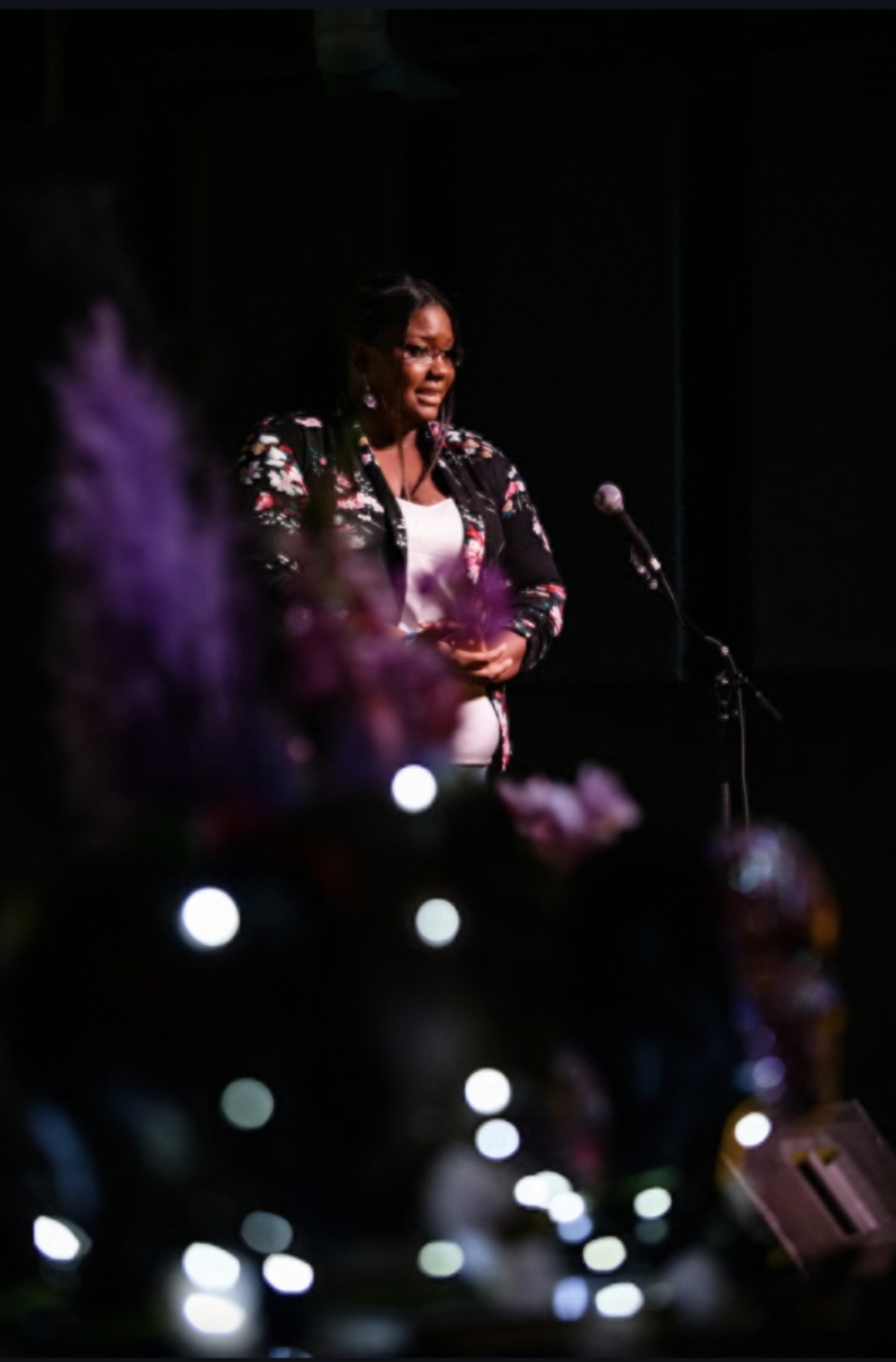 A wider view of Erica onstage, surrounded by the intimate lighting and atmosphere of the Art Week gathering.