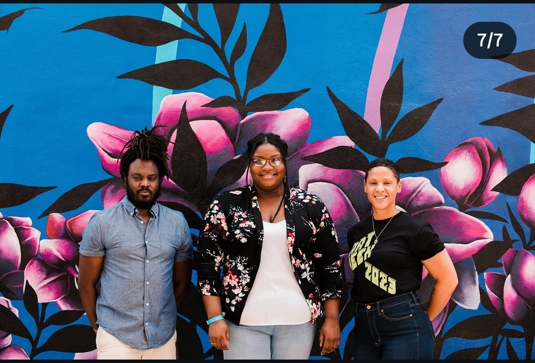 Erica poses with fellow attendees in front of a vivid floral mural during Des Moines Art Week.